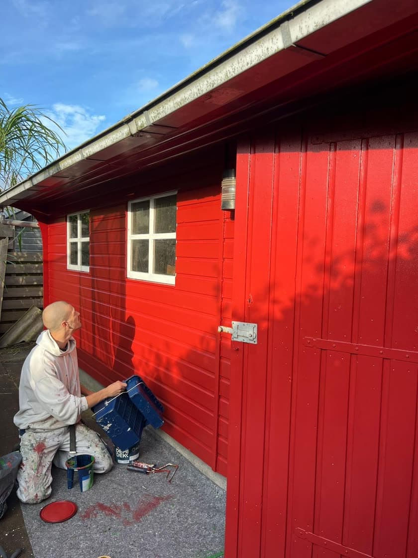 Stef aan het werk aan een rood geschilderde schuur